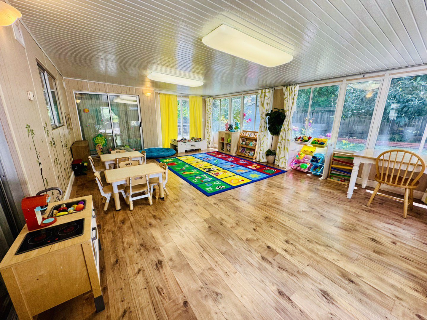 Bright and colorful early childhood classroom with wooden floors and learning stations.