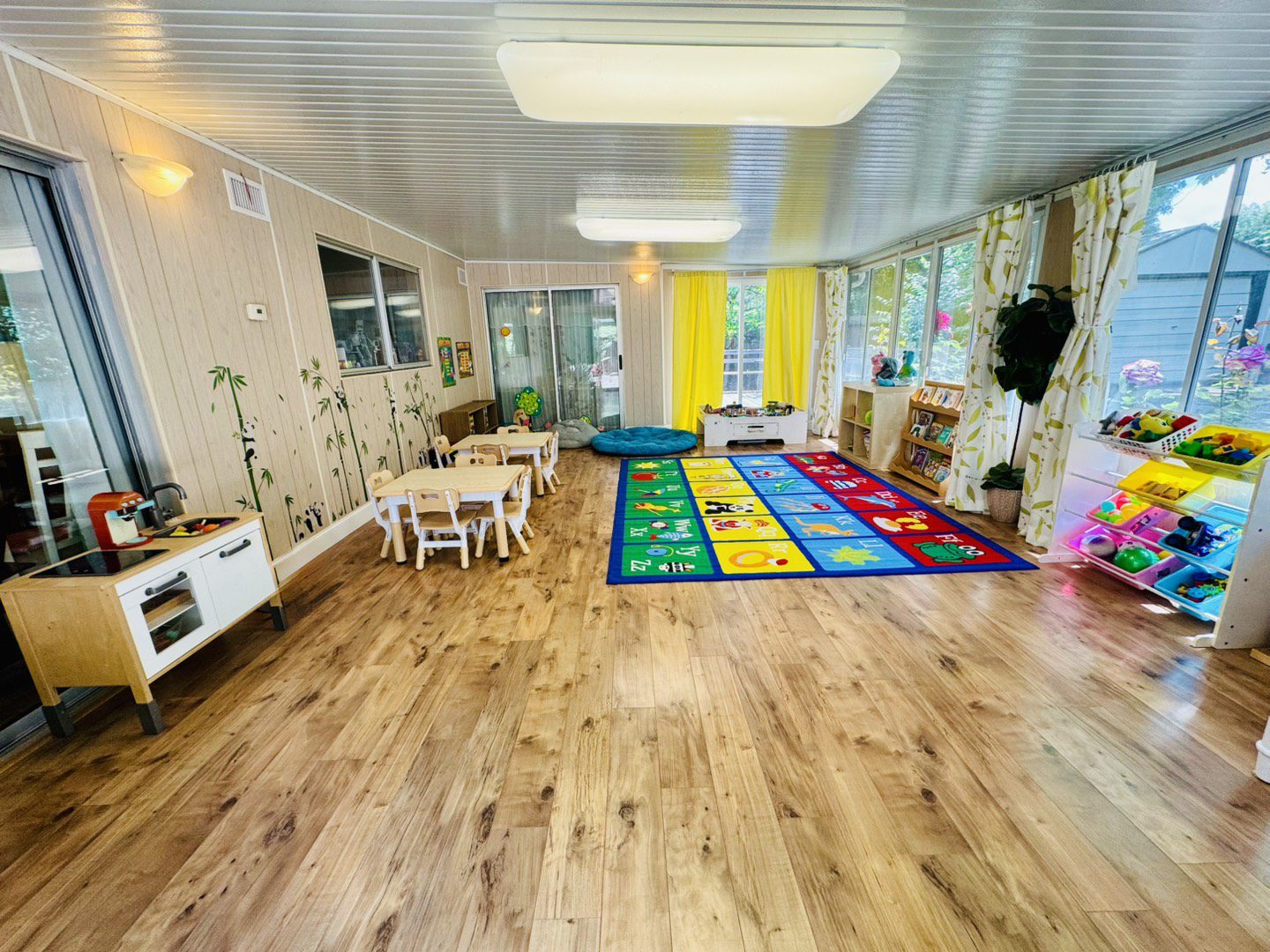Bright and cheerful children's playroom with colorful rug and small tables.