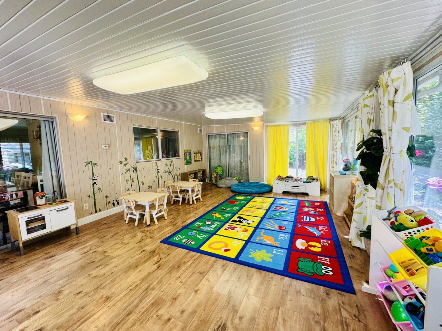 Bright and cheerful children's playroom with colorful alphabet carpet and white furniture.