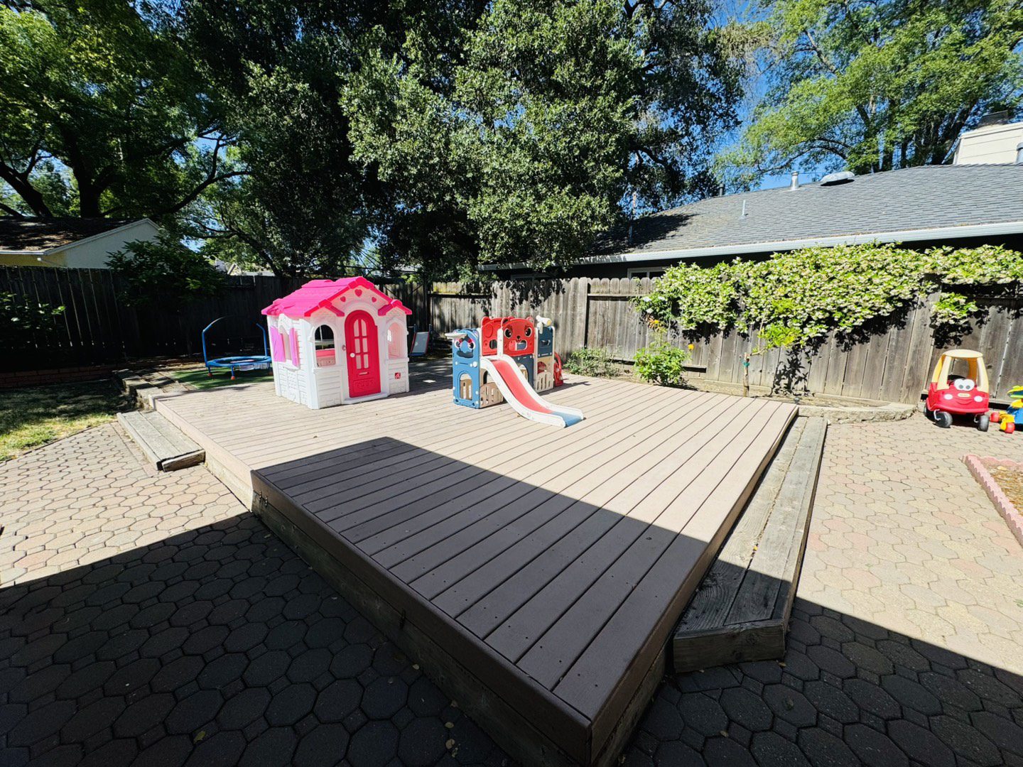 Children's playground with a playhouse and slide in a sunny backyard.