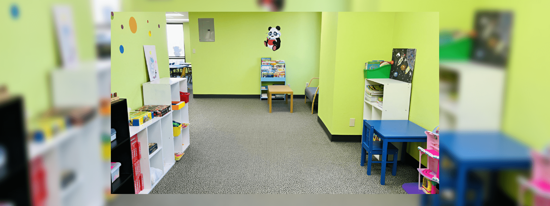 A children's playroom with colorful shelves and a small table against a green wall.