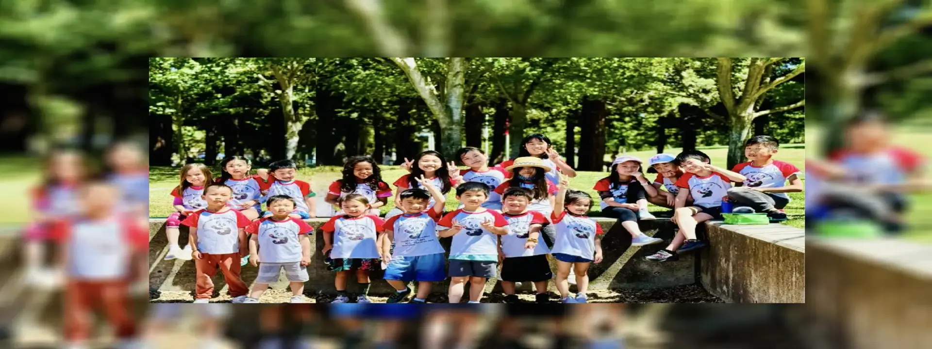 Group of children and adults posing outdoors with peace signs and colorful hats.